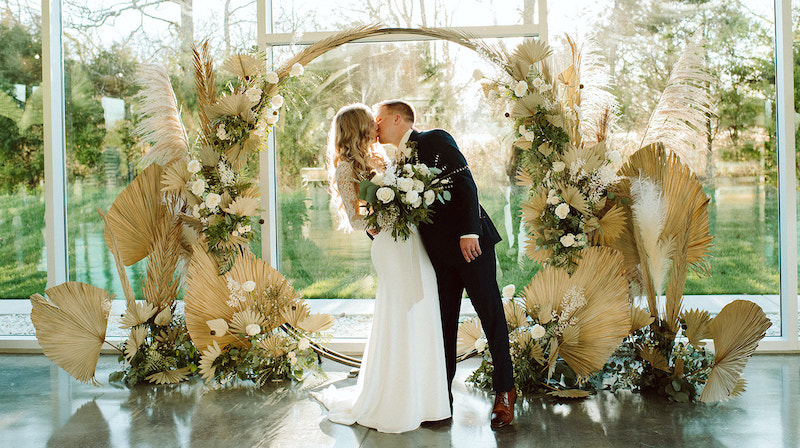 Bride and Groom Kissing Under Floral Arbor