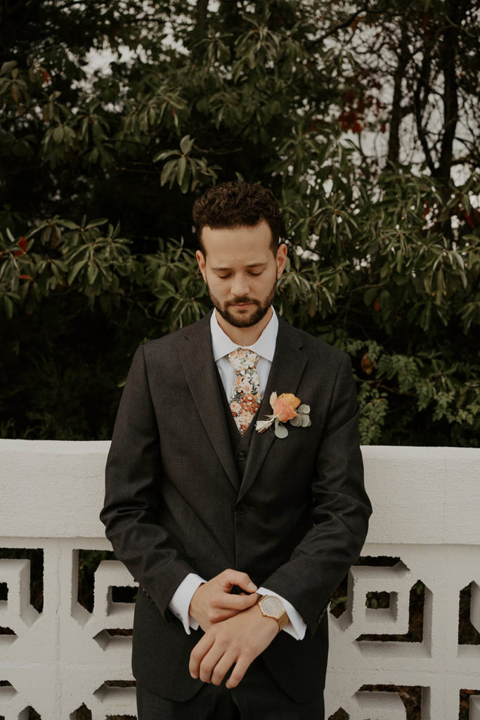 Groom wearing boutonniere, fixing suit cuffs