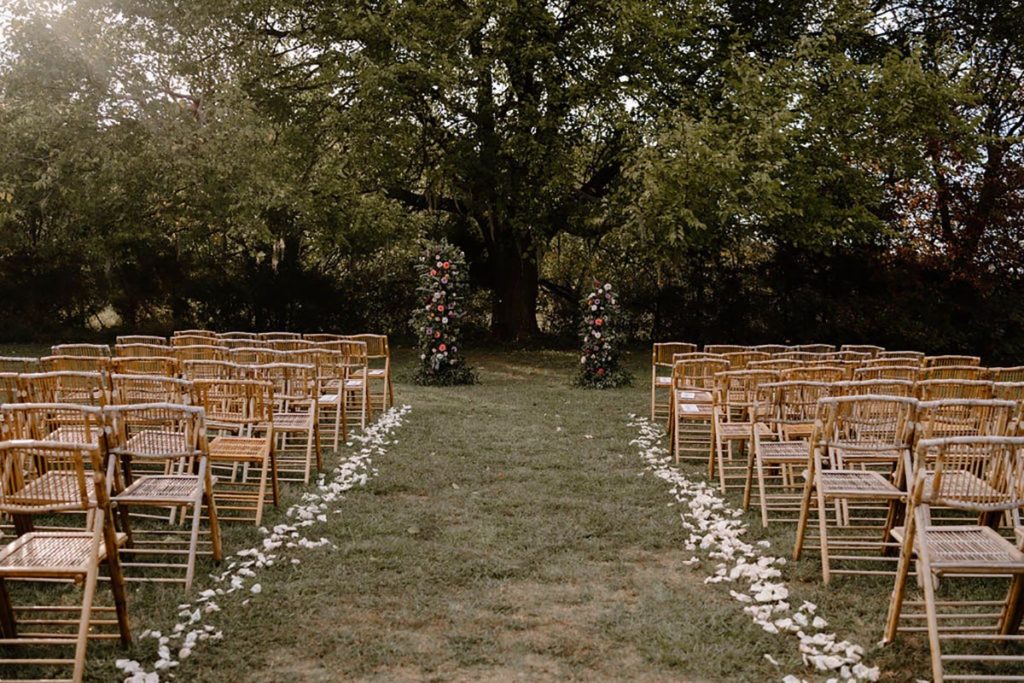 Ceremony set up for the wedding. Wooden chairs with large floral pillars at the end of the aisle.
