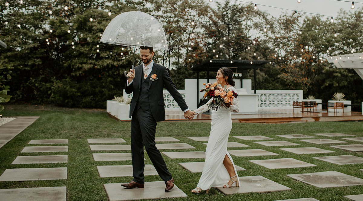 Bride and groom walking through the rain with smiles