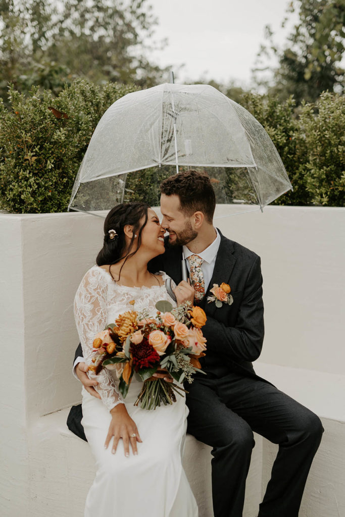 Outdoor portrait of bride and groom kissing in the rain