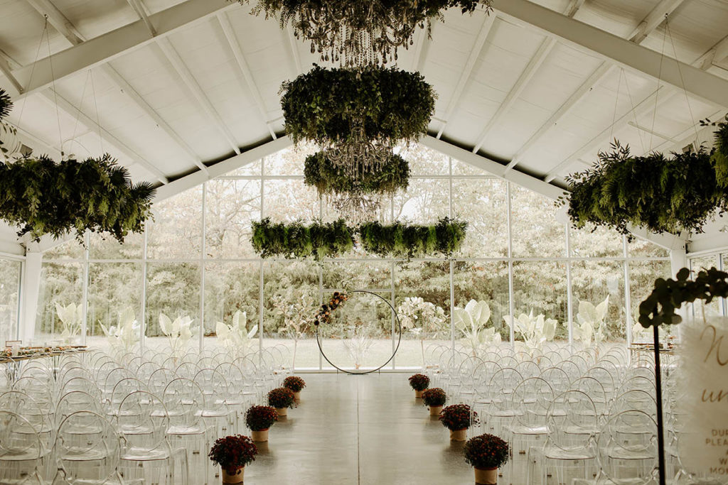 Wide shot of ceremony set up with mums down the aisle and circular floral arbor