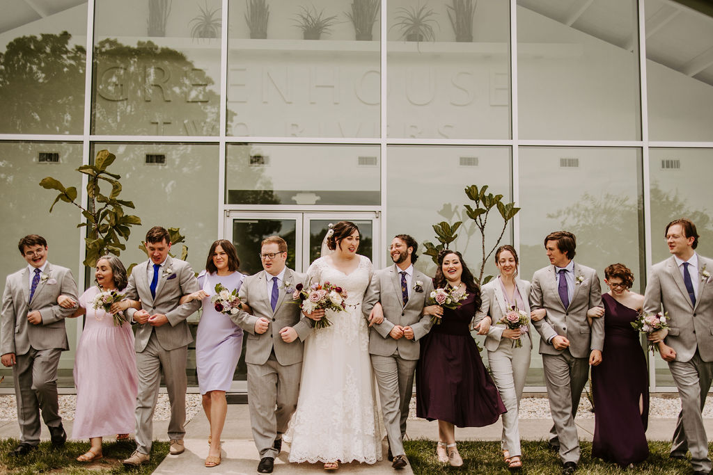 Entire Wedding Party Linking Arms with Flowers in Hand