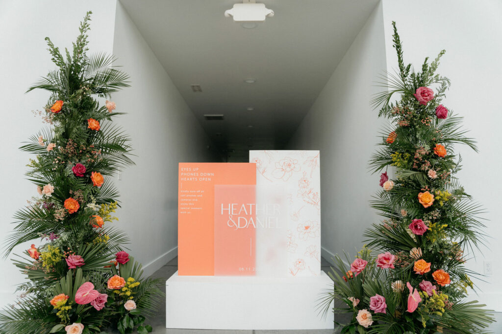 Salmon and white welcome sign in between two 7 foot floral pillars