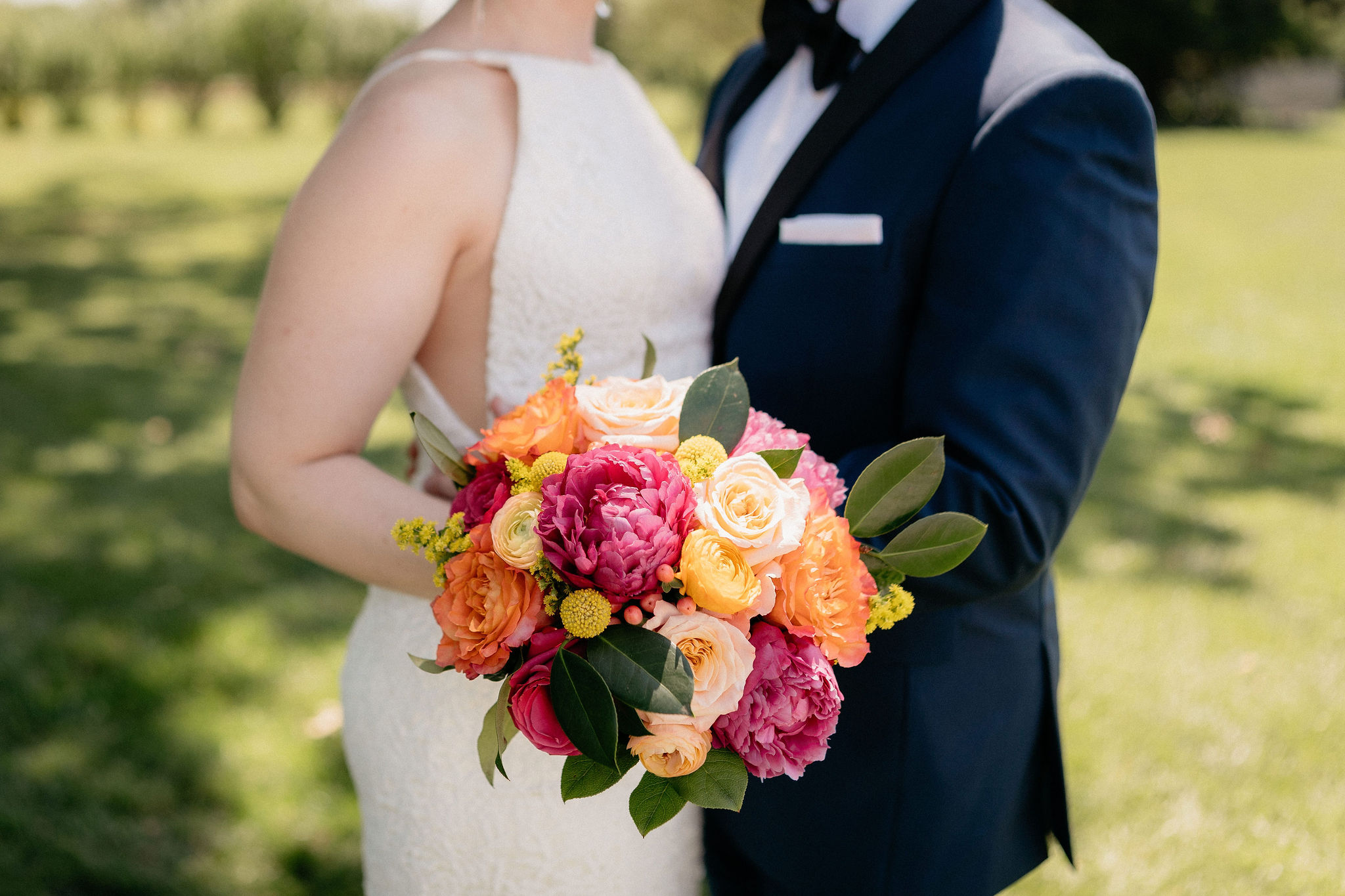 Bride and groom holding bouquet in sherbet colors