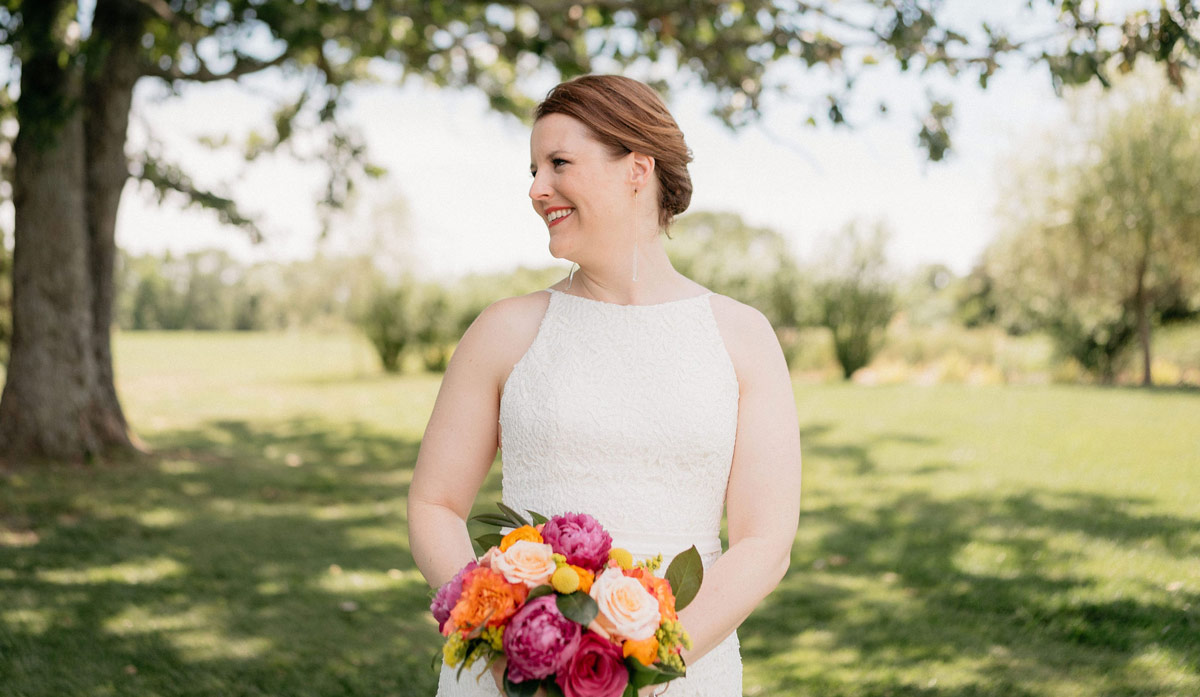 Bride holding her bouquet in warm summer color palette, looking to the side