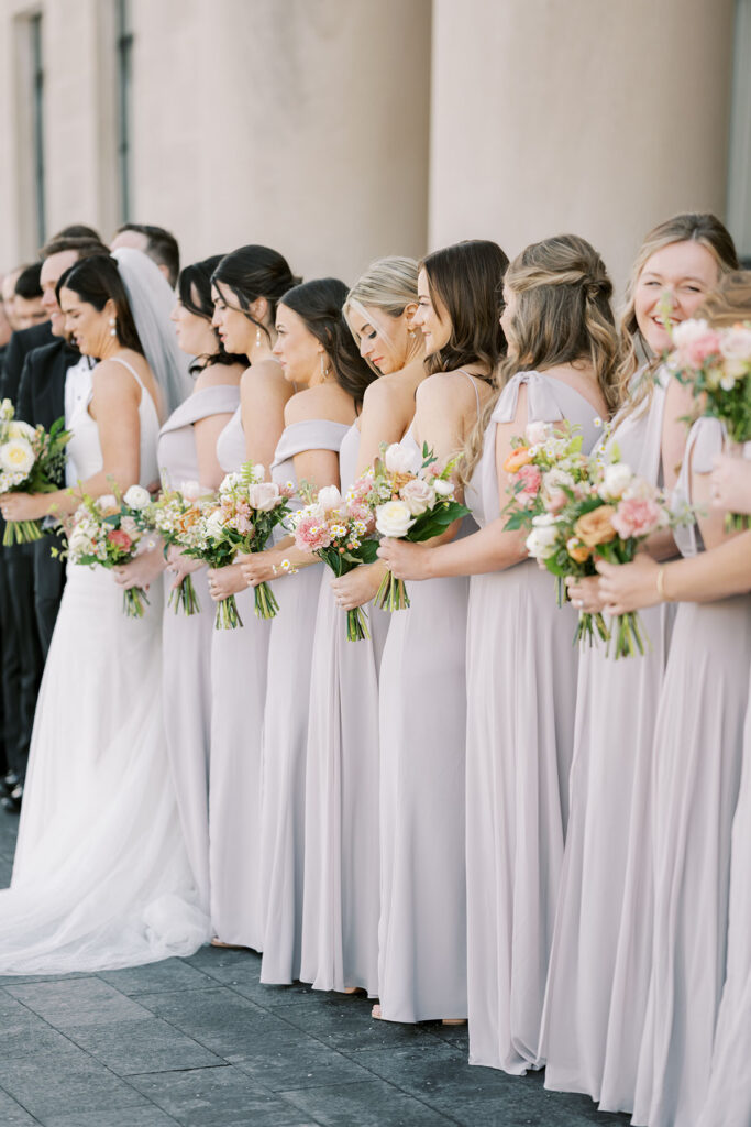 Bridesmaids lined up holding muted pastel bouquets