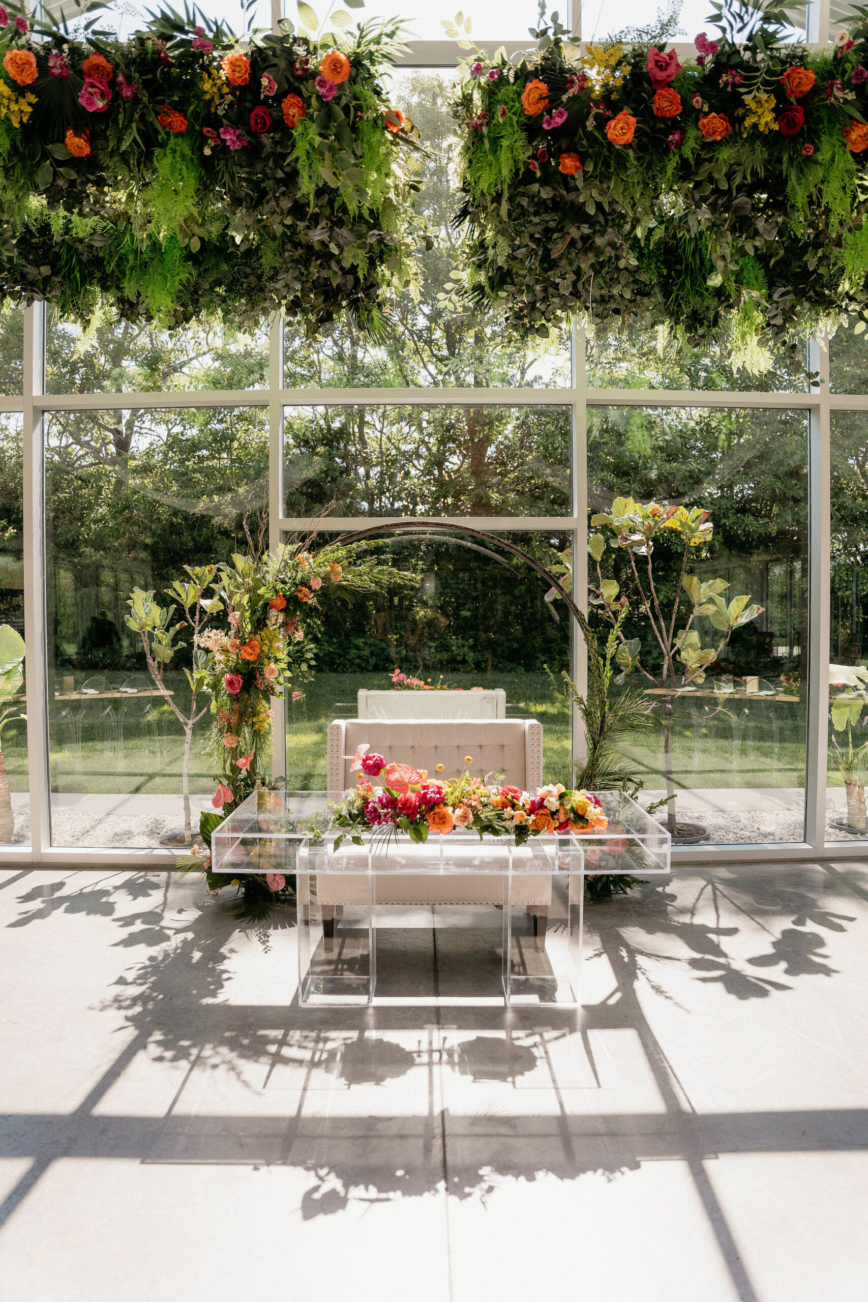 Sweetheart table with floral arbor behind and floral installations above at Greenhouse Two Rivers