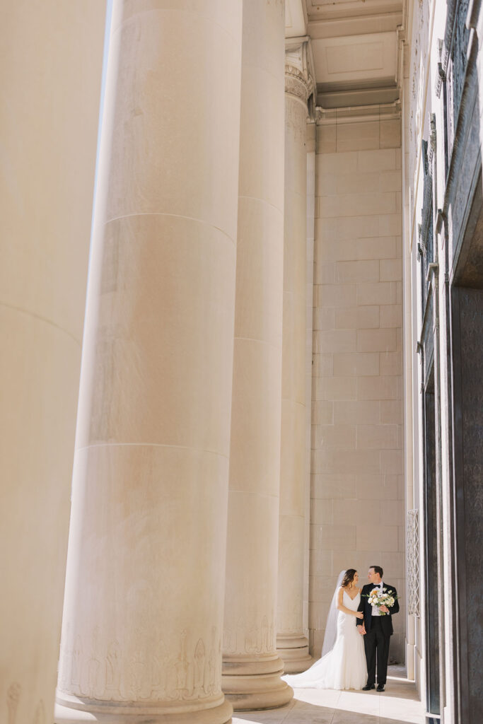 Zoomed out photo of bride and groom next to dramatic pillars