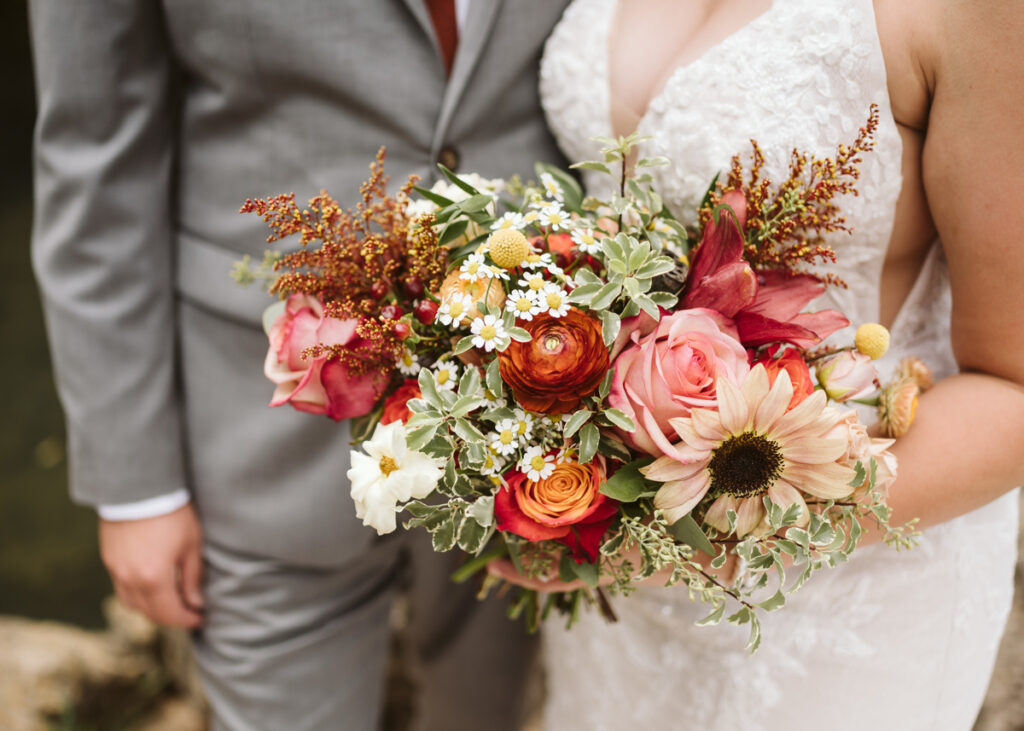 Fall wedding bouquet with ranunuculus, sunflowers, goldenrod, and roses