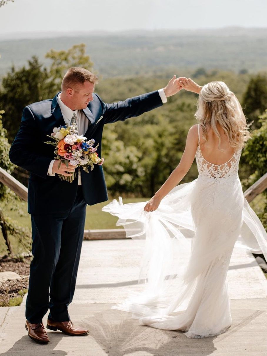 Newlyweds twirling while groom holds bouquet