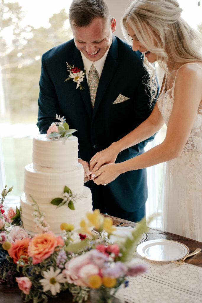 Couple cutting the cake with a ring of flowers in front of it