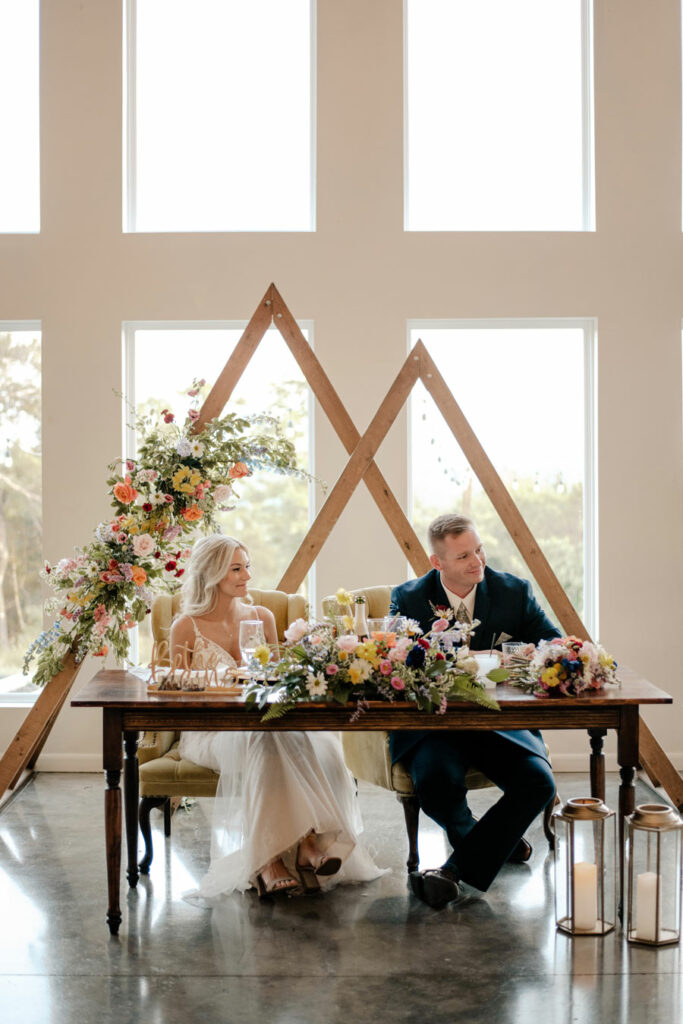 Couple sitting at their sweetheart table with large triangles behind them