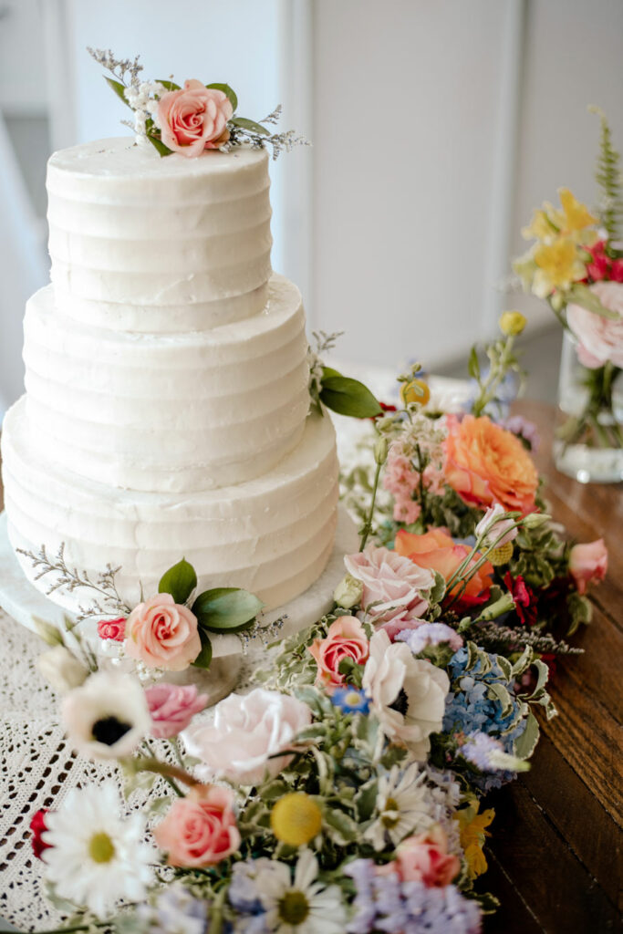 Lush floral arrangement around the white cake