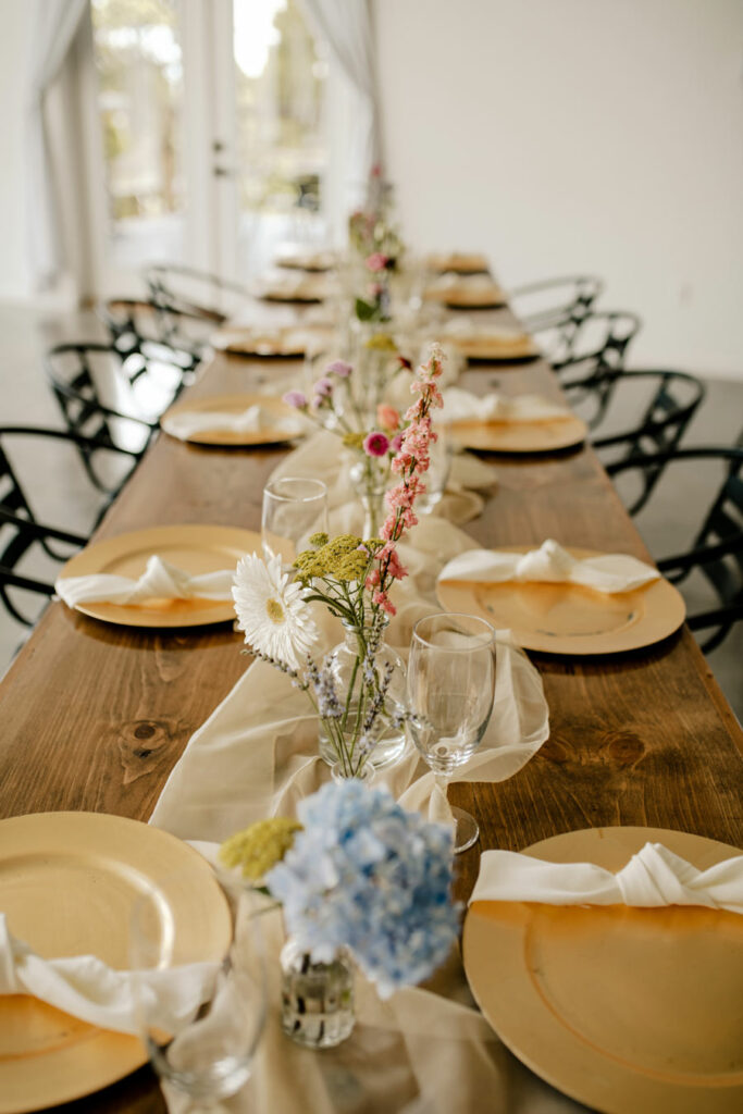 Bud vases going down a long guest table with colorful flowers