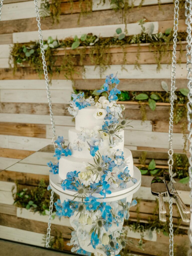 White cake with small blue and white flowers cascading down.