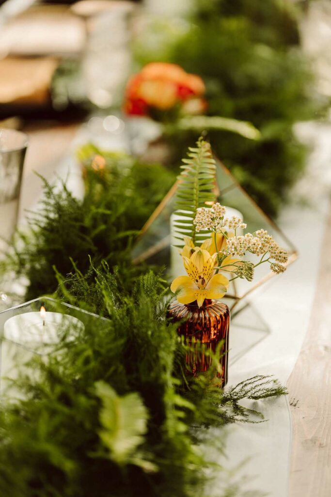 Close up of table garland and a bud vase with yellow flowers