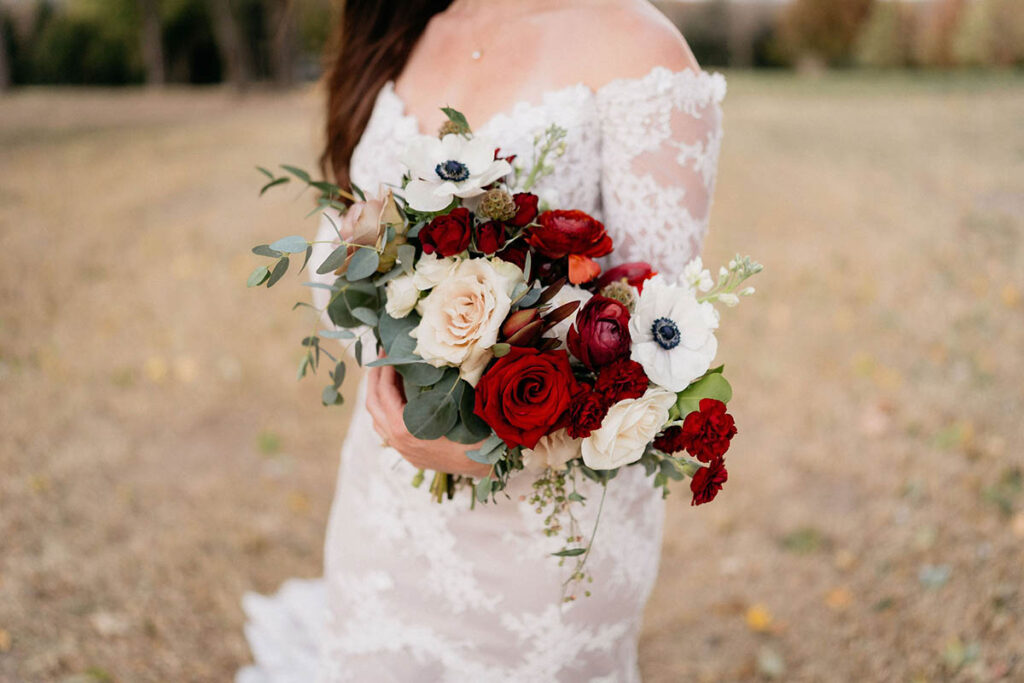 Bride holding moody bouquet with off-the-shoulder long sleeve dress