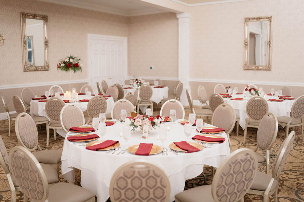 Round table with red centerpiece and napkins in ballroom