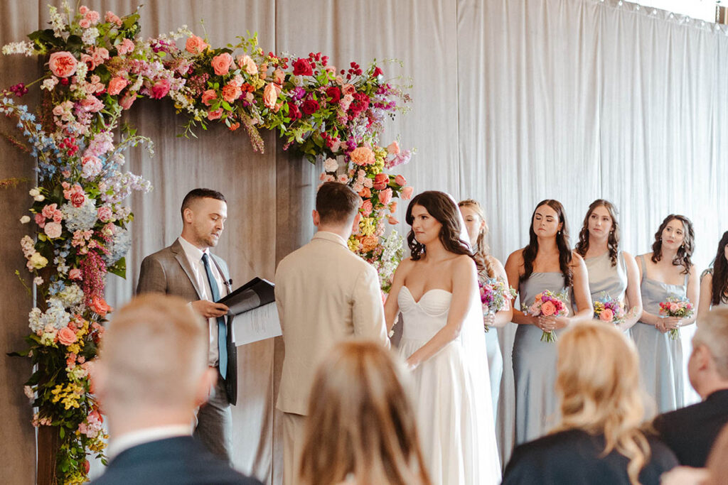 Wedding Ceremony looking at the couple and the arch with the bridesmaids in the background