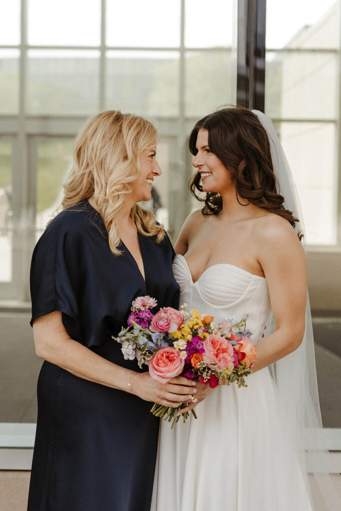 Bride and her mom sharing a happy moment holding her bouquet