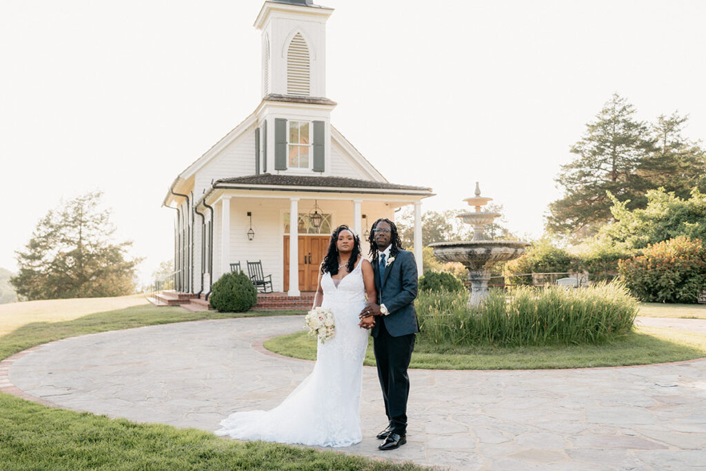 Bride and groom portrait looking at the camera with a white chapel in the background