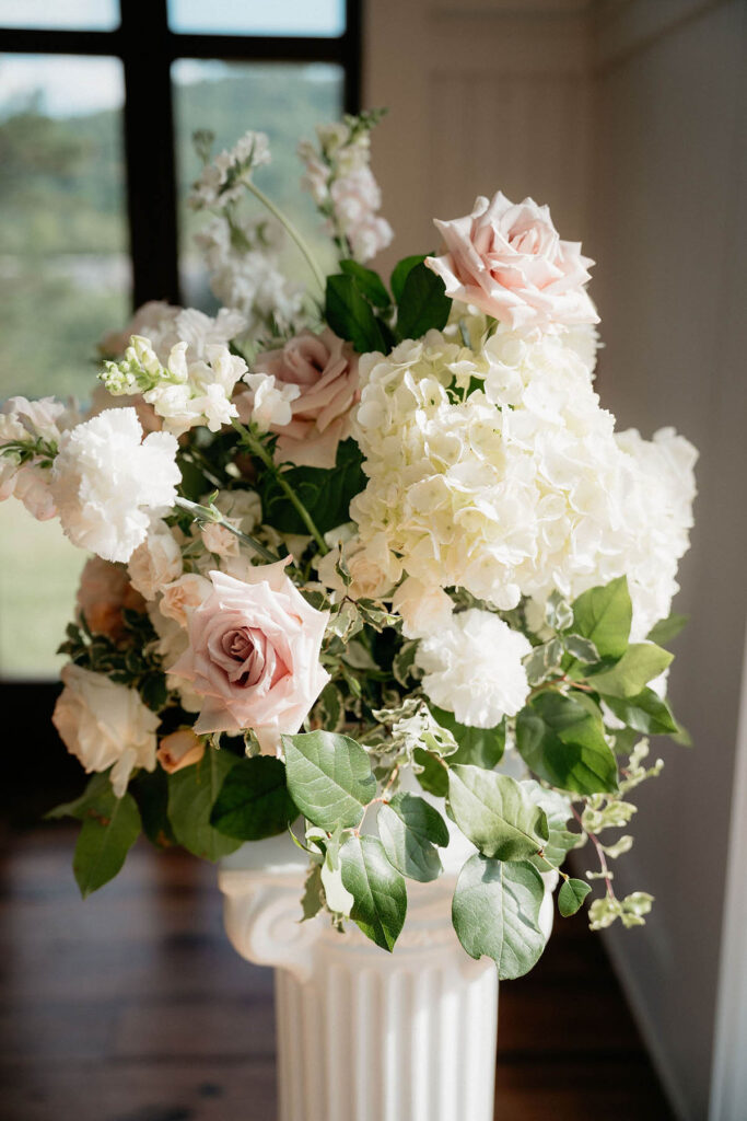 Close up of ceremony statement florals with white hydrangea, blush roses, snapdragons, and scabiosa