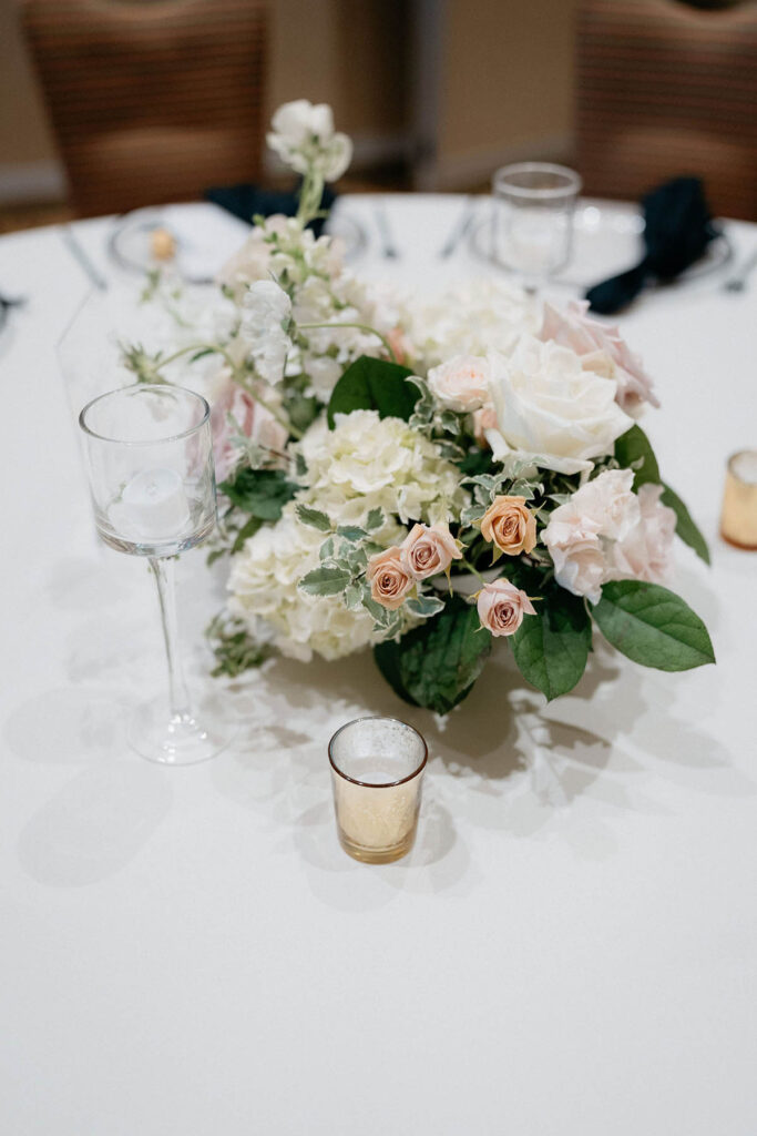 Guest table centerpiece with hydrangea, roses, stock, and scabiosa