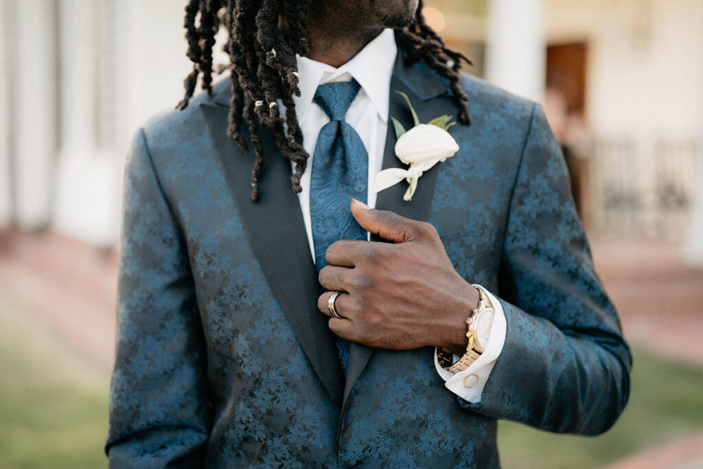 Close up of groom's white ranunculus boutonniere and navy paisley suit