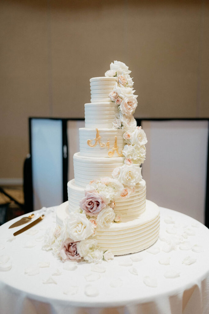 Six-tier white wedding cake with flowers cascading down the side